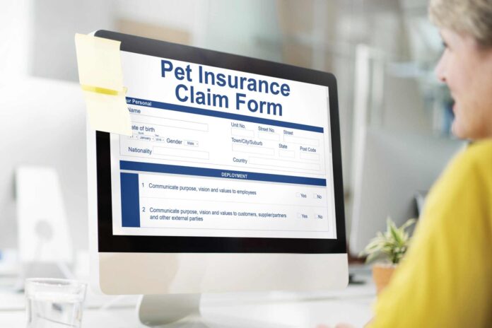 A female at her computer filling out a pet insurance claim form.